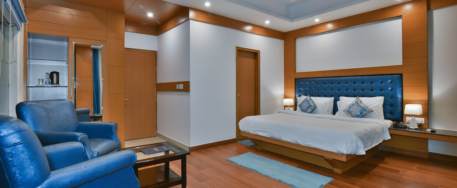 A large bed placed in front of two sofas at the Luxury Room Without Balcony at DLS Highland Resort and Spa, Mussoorie.